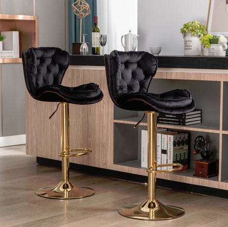 Two black velvet Plush height adjustable bar stools with gold bases in a modern kitchen setting.