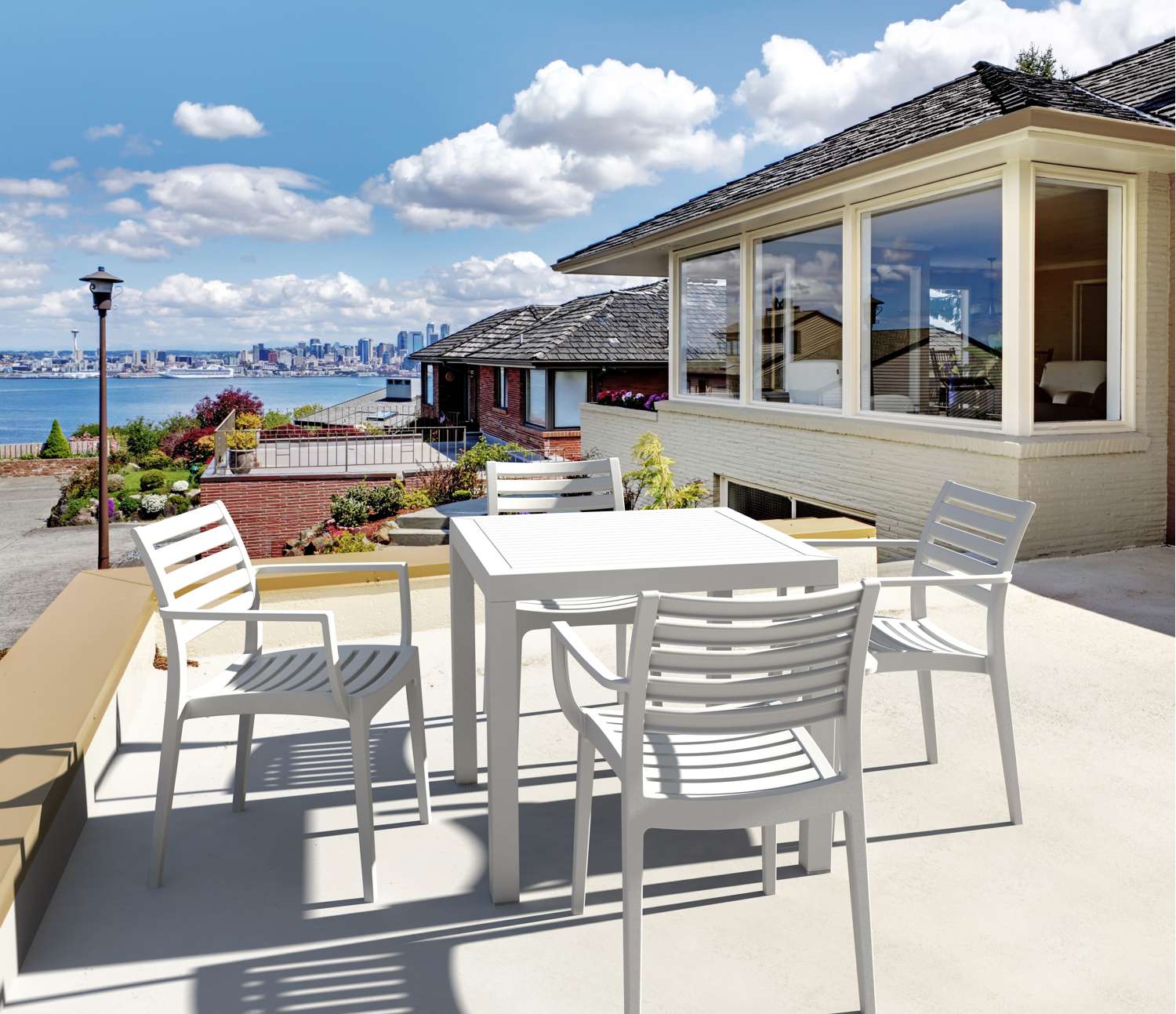 Siesta Artemis Outdoor patio set with table and chairs on a deck overlooking a scenic view.