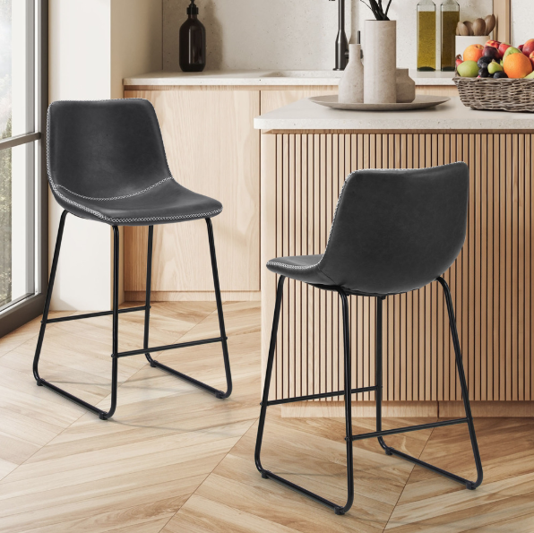 Two Grey Phoebe PU vinyl bar stools in a kitchen setting with wooden flooring and cabinets.